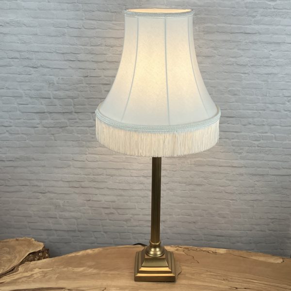 off white bowed empire traditional lampshade with matching fringe shown on a table lamps