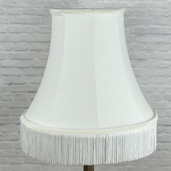 Natural off white bowed lampshade with fringe shown switched off