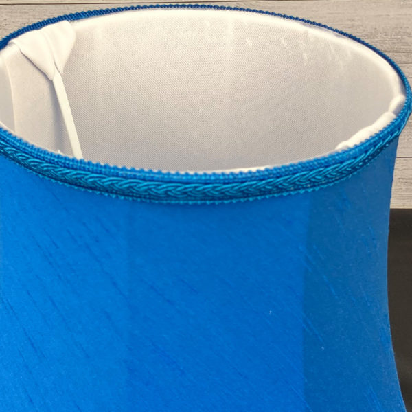 Close up image of the Retro Bright Blue Cruise Faux Silk Lampshade with a Matching Plait Trim. Showing the soft white internal lining.