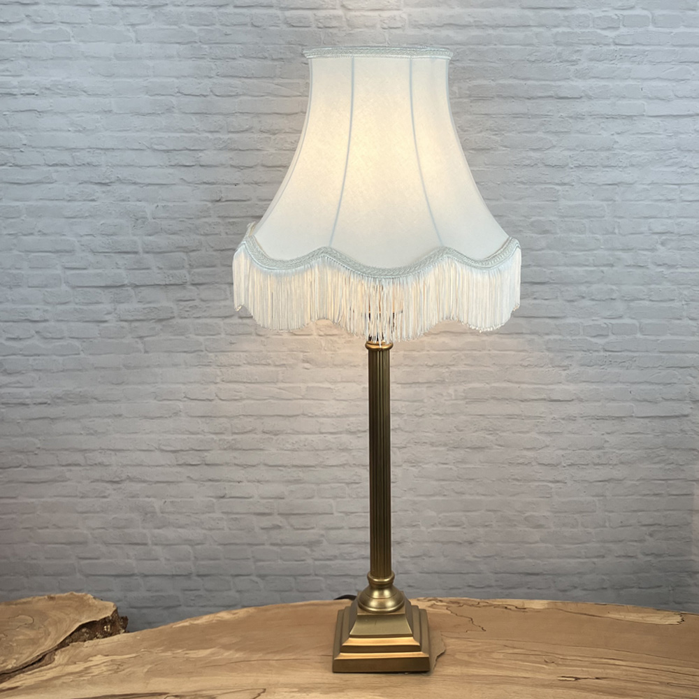 Off white scalloped bowed empire lampshade with matching natural fringe shown on a table lamp