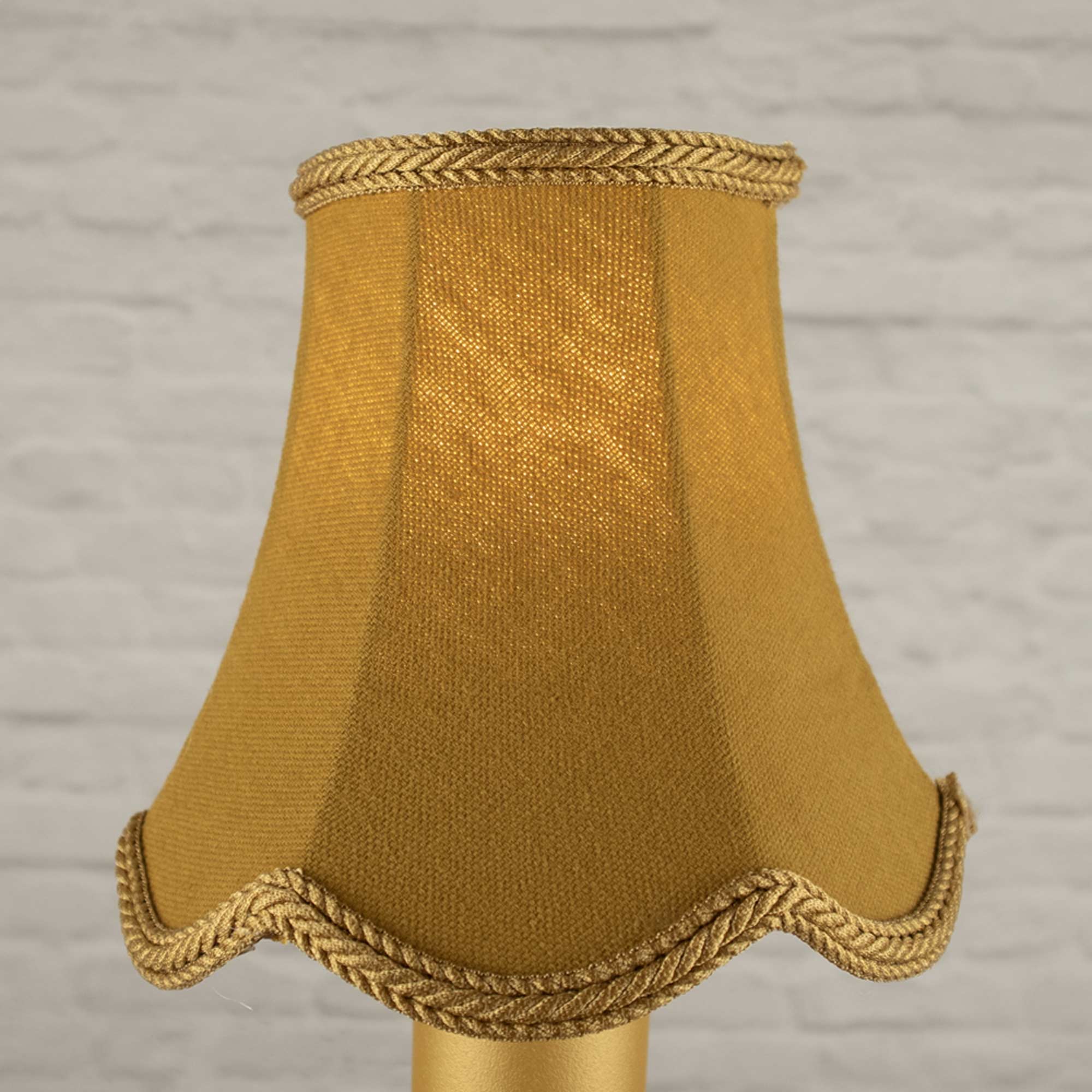 Image of the scalloped gold candle shade with a lit bulb