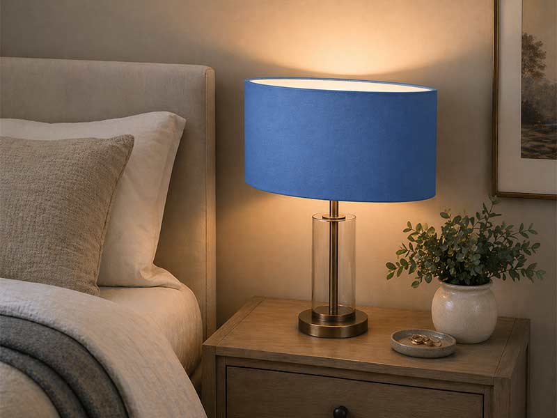 Blue oval lampshade on a bedside table lamp in a modern bedroom