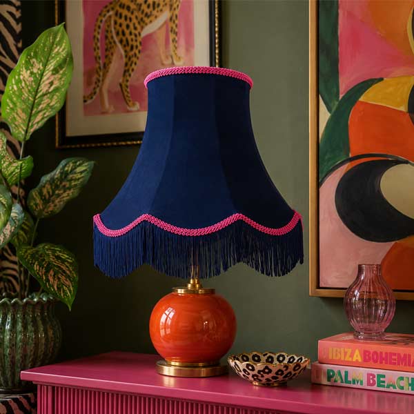 Handmade navy velvet scalloped table lampshade with pink trim and navy fringe displayed on an elegant table lamp.