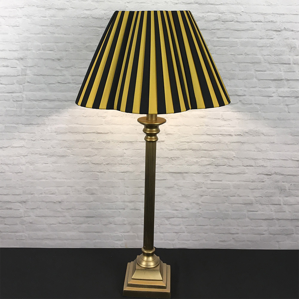 Black and gold striped daisy pleated lampshade on a brass table lamp base