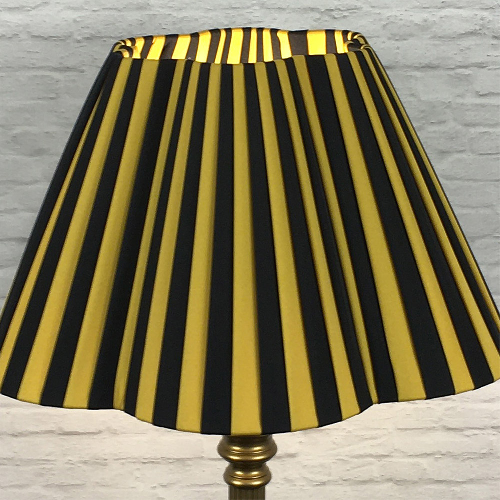 Black and gold striped daisy pleated lampshade on a brass standing floor lamp base