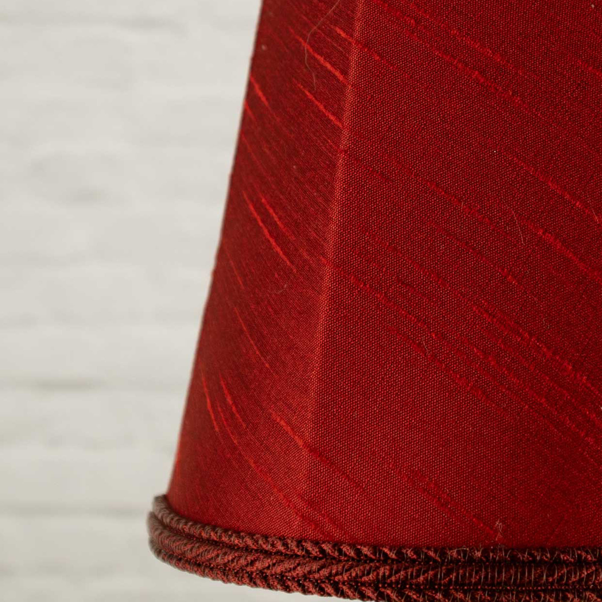 Close-up of burgundy faux silk fabric showing dupion slub texture on empire chandelier shade