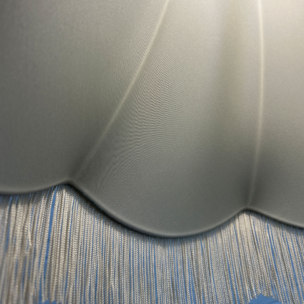 Close-up of dark cream fringe and cream lining on teal brushed cotton scalloped bowed empire lampshade