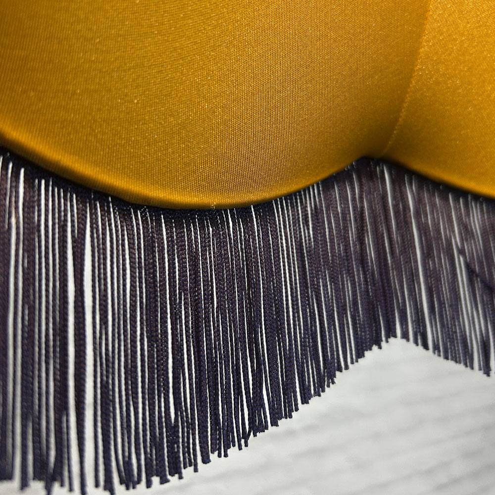 Close-up of navy fringe and gold lining on navy velvet scalloped bowed empire lampshade