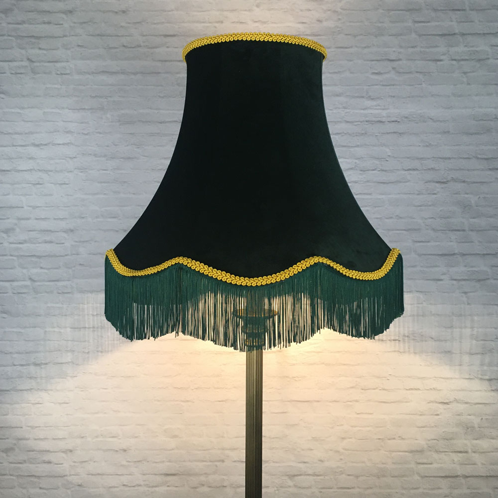 Illuminated dark green velvet scalloped bowed empire lampshade with yellow feather trim and green fringe on floor lamp
