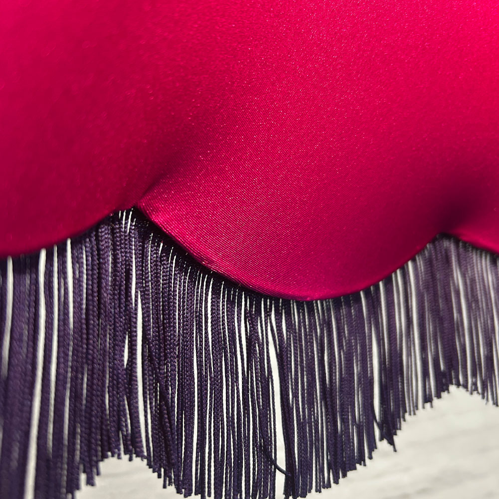 Close-up of navy fringe and pink lining on navy velvet scalloped bowed empire lampshade