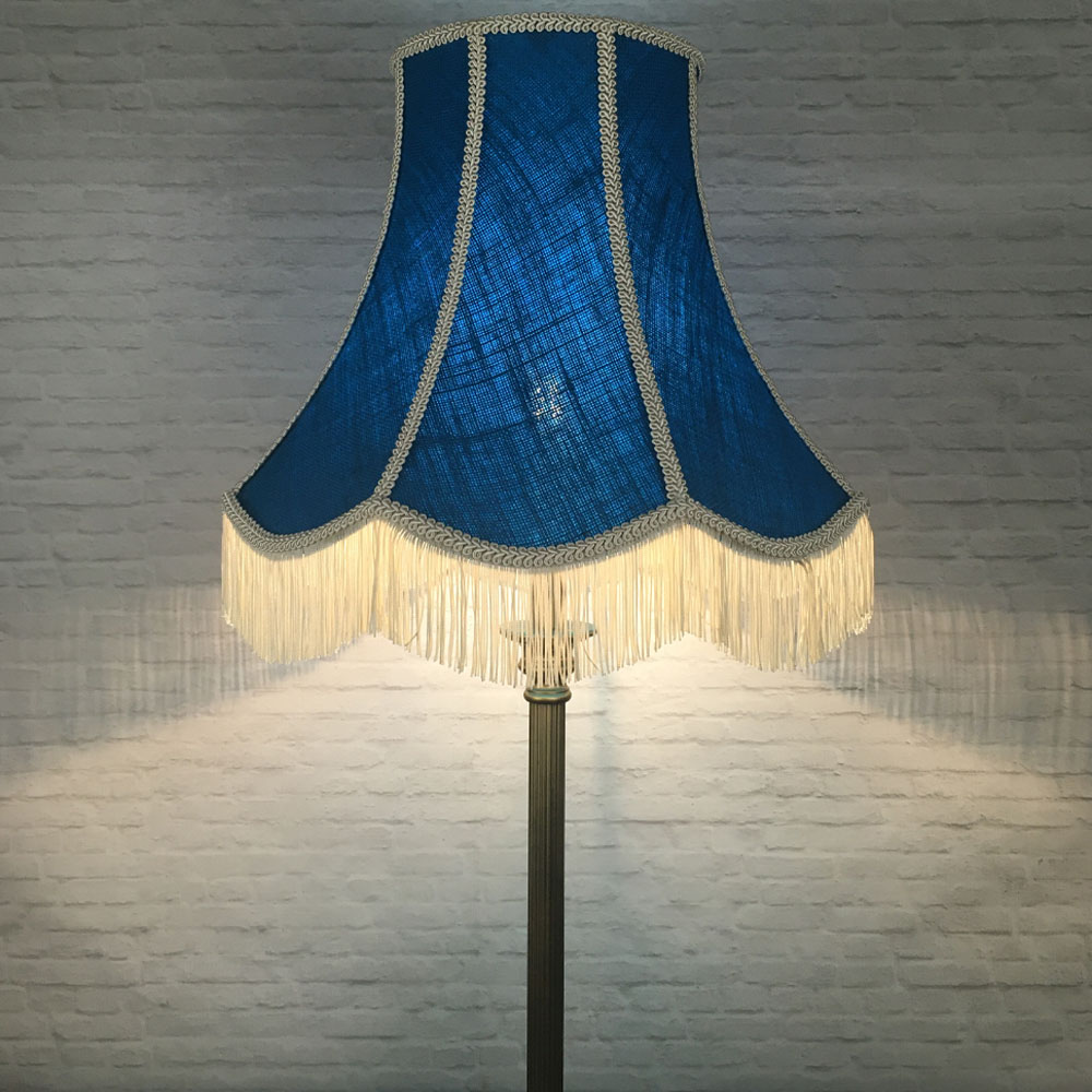 Illuminated blue hessian scalloped bowed empire lampshade with pink trim and pink fringe on floor lamp
