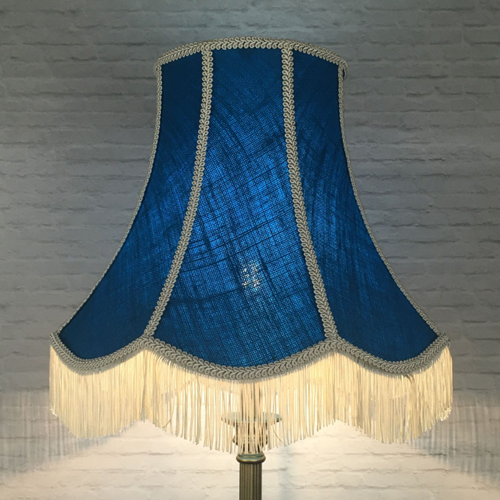 Illuminated blue hessian scalloped bowed empire lampshade with pink trim and pink fringe on floor lamp
