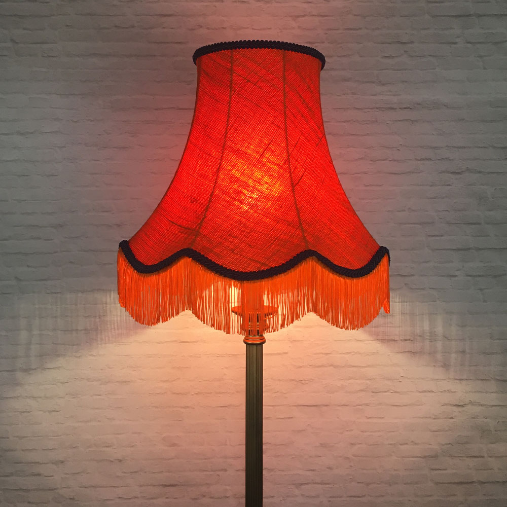 Illuminated orange hessian scalloped bowed empire lampshade with navy trim and fringe on floor lamp