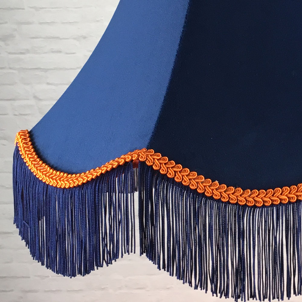 Close-up of navy velvet lampshade with orange feather trim and navy fringe detail