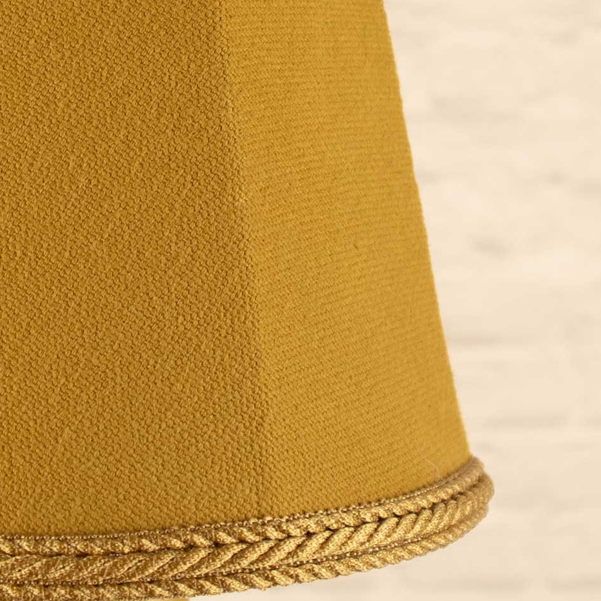 Close-up of old gold brushed cotton fabric and matching rope trim on empire candle shade