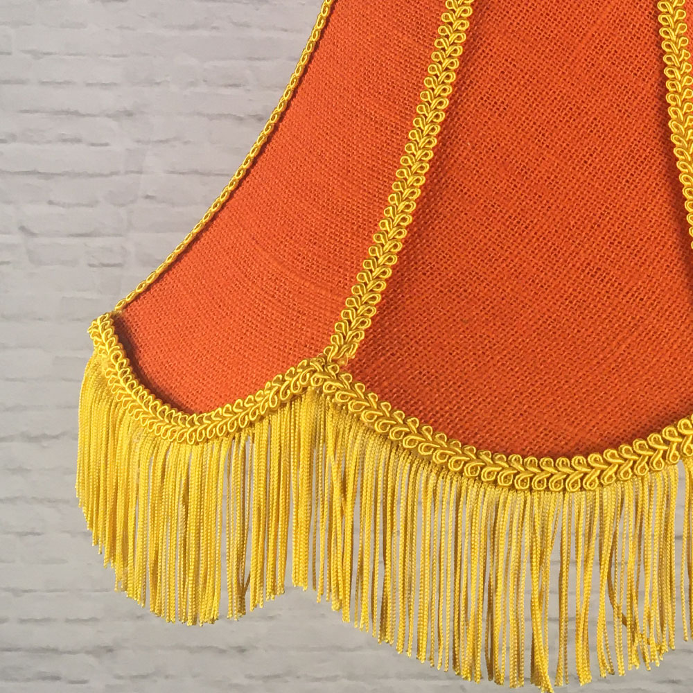 Close-up of orange hessian lampshade with yellow trim and fringe detail