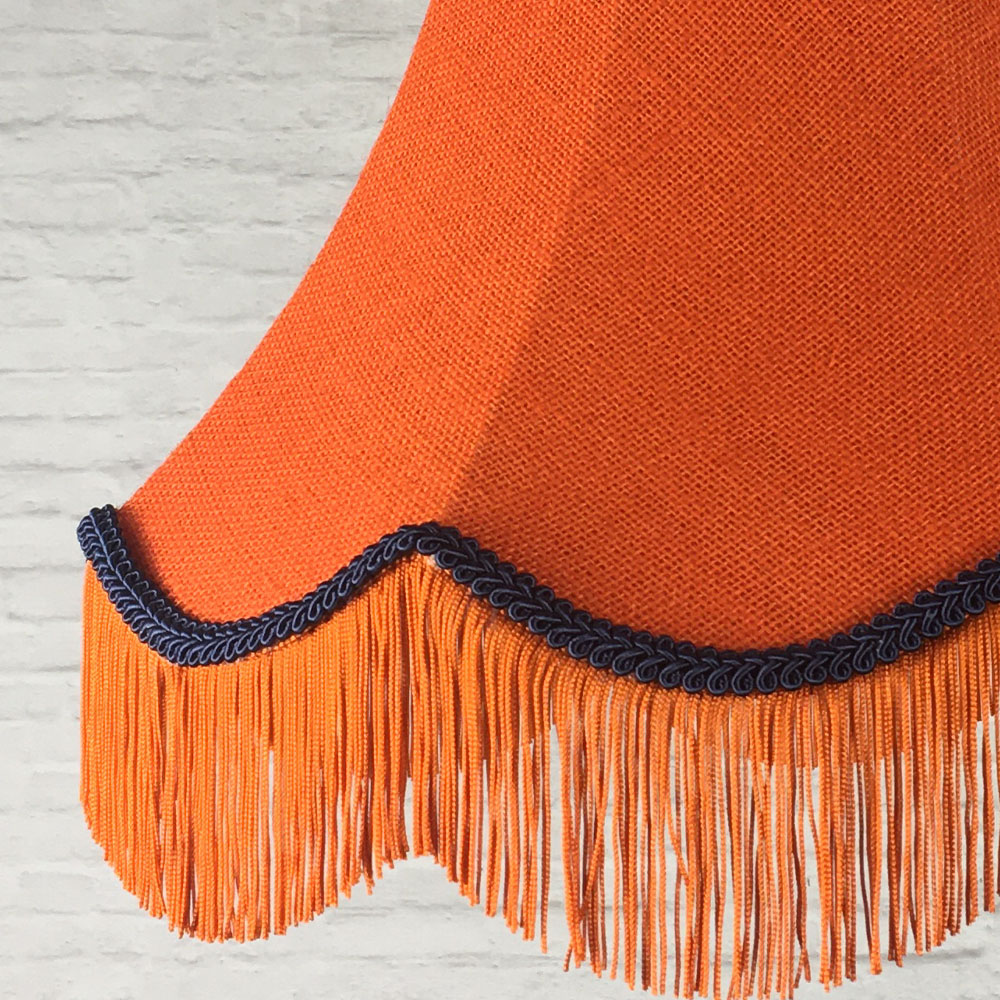 Close-up of orange hessian lampshade with navy trim and fringe detail