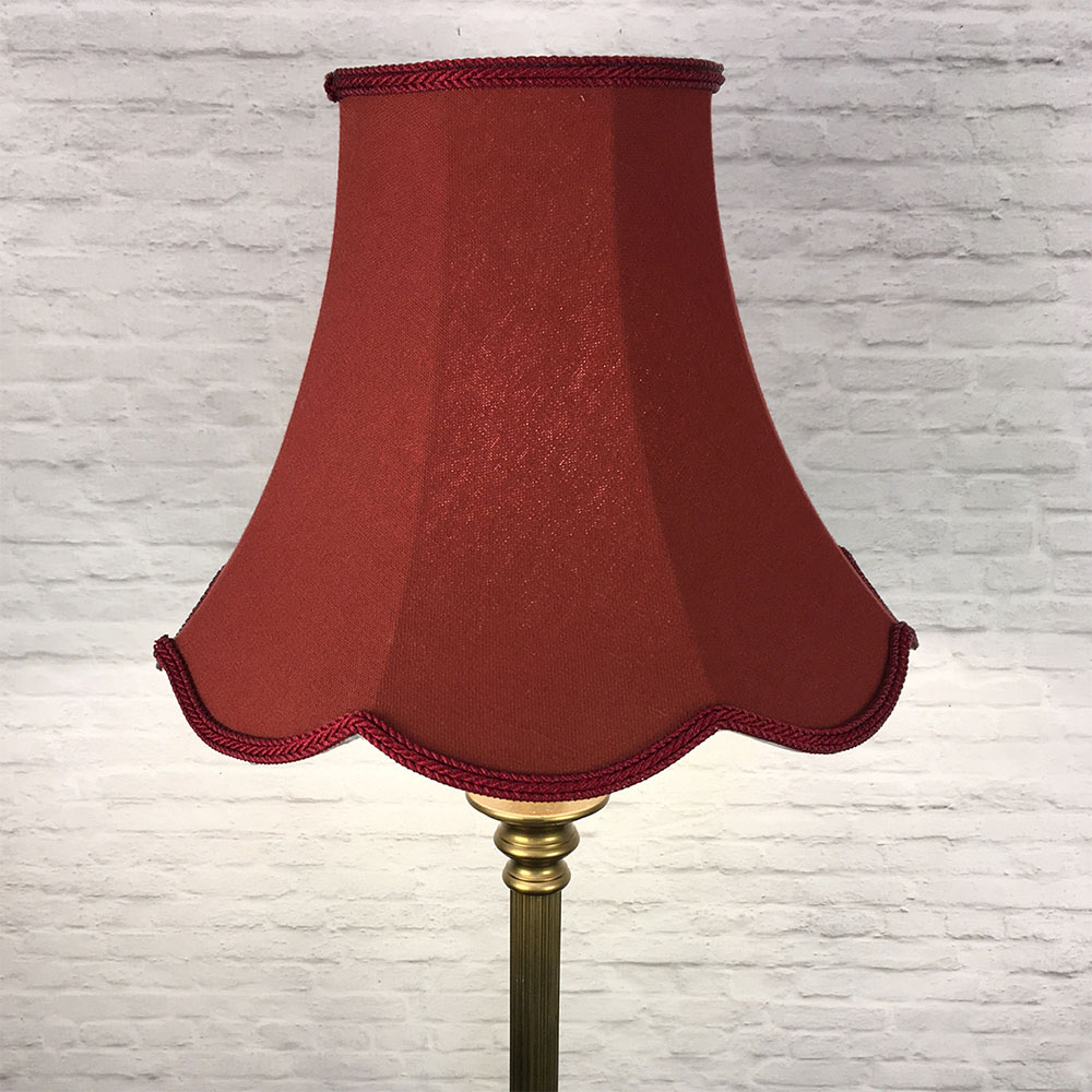 Illuminated ruby scalloped bowed empire lampshade on antique brass standing lamp
