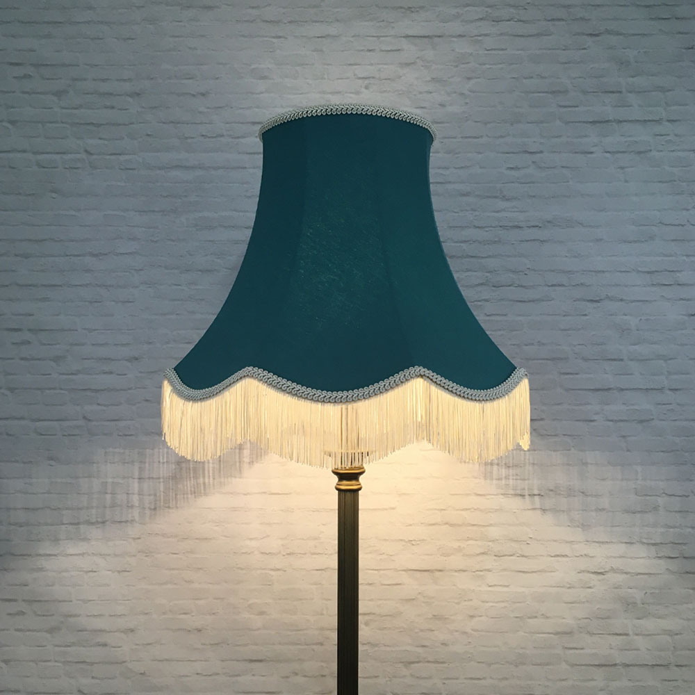 Illuminated teal brushed cotton scalloped bowed empire lampshade with dark cream feather trim on table lamp