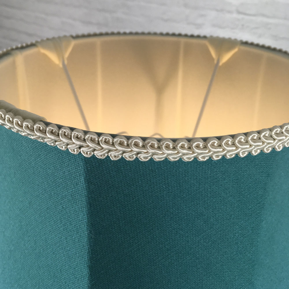 Close-up of dark cream feather trim, teal brushed cotton fabric and cream lining on scalloped bowed empire lampshade