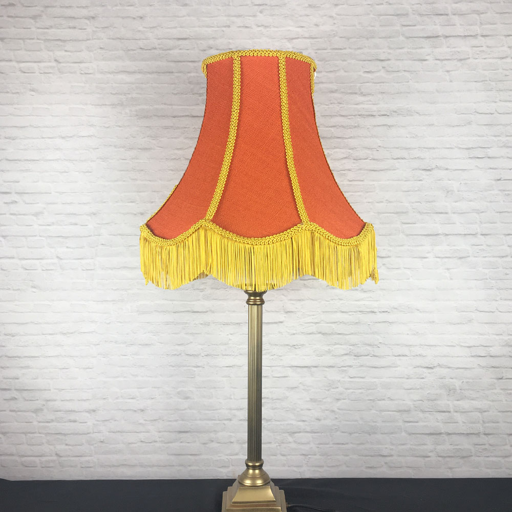 Orange hessian scalloped bowed empire lampshade with yellow trim and fringe on table lamp