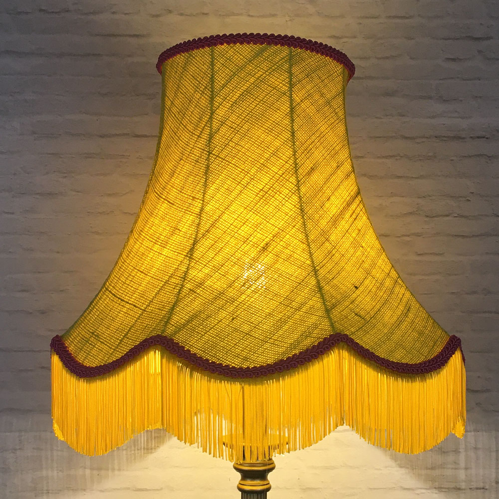 Illuminated yellow hessian scalloped bowed empire lampshade with pink trim on floor lamp