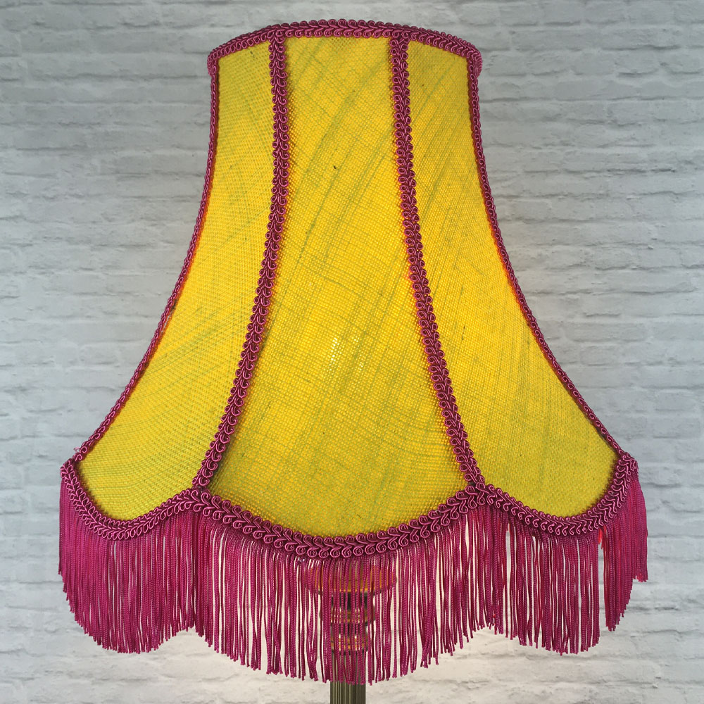 Illuminated yellow hessian scalloped bowed empire lampshade with pink trim and pink fringe on floor lamp