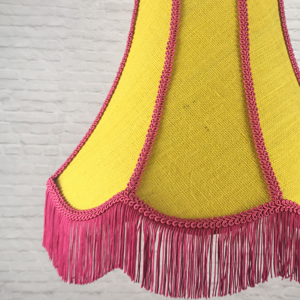 Close-up of yellow hessian lampshade with pink trim on struts and fringe detail