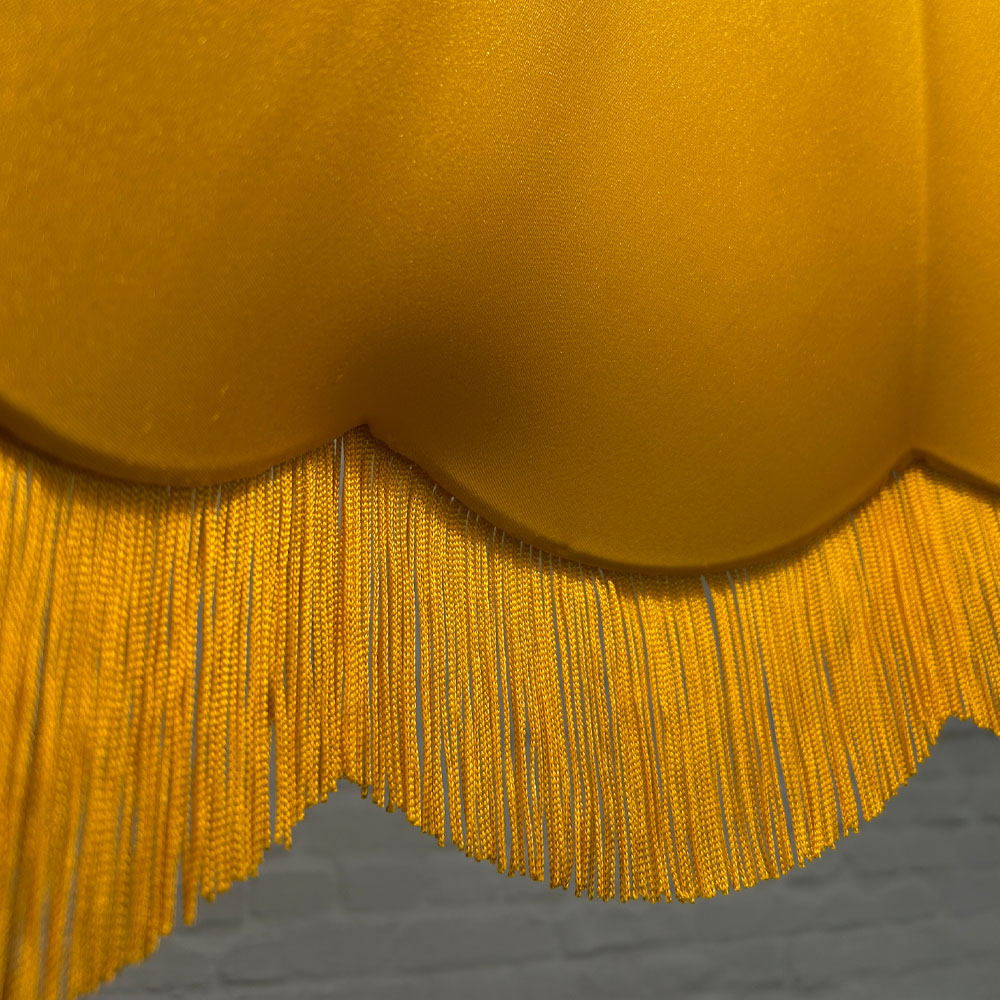 Close-up of lampshade lining and yellow fringe on yellow hessian scalloped bowed empire shade